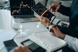 Business professionals reviewing financial charts on digital devices in a modern office setting.